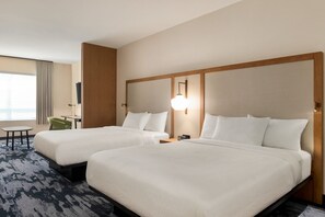Habitación de hotel con dos camas, un escritorio, una silla y un ventanal grande.