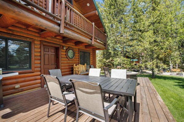 A log cabin with a deck, outdoor seating, and a large window.