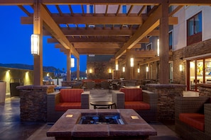 Un patio al aire libre con paredes de piedra, muebles de mimbre y una chimenea de piedra.