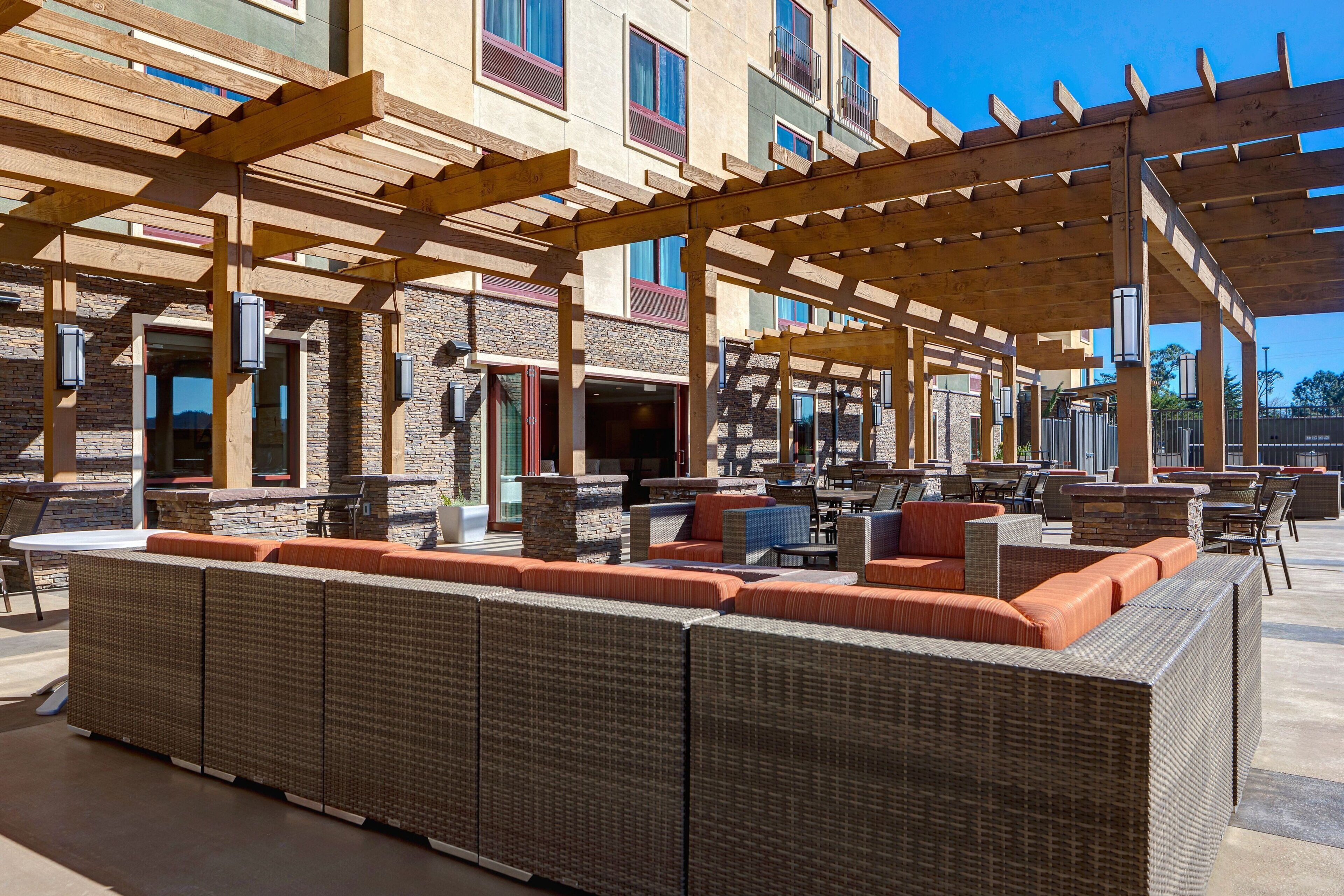 An outdoor patio area with wicker furniture, wooden pergolas, and stone accents.