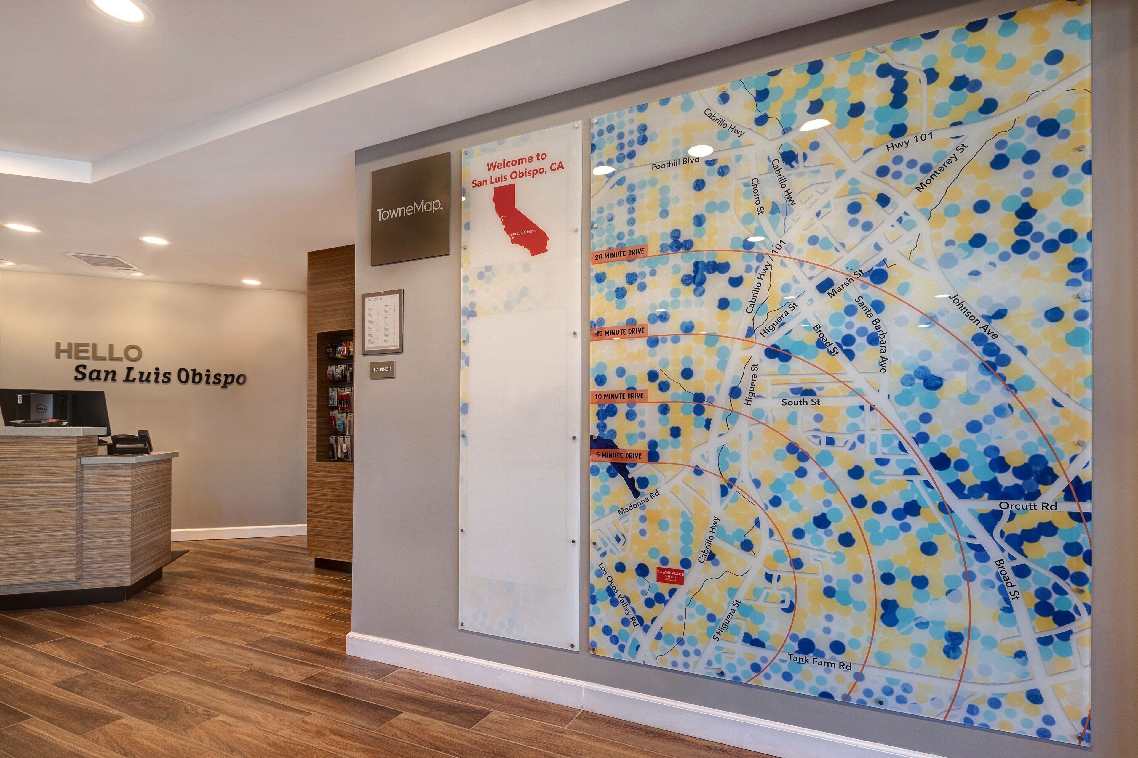 Un área de recepción con un mapa de San Luis Obispo, California, un mostrador de recepción y un cartel que dice 'HELLO San Luis Obispo'.