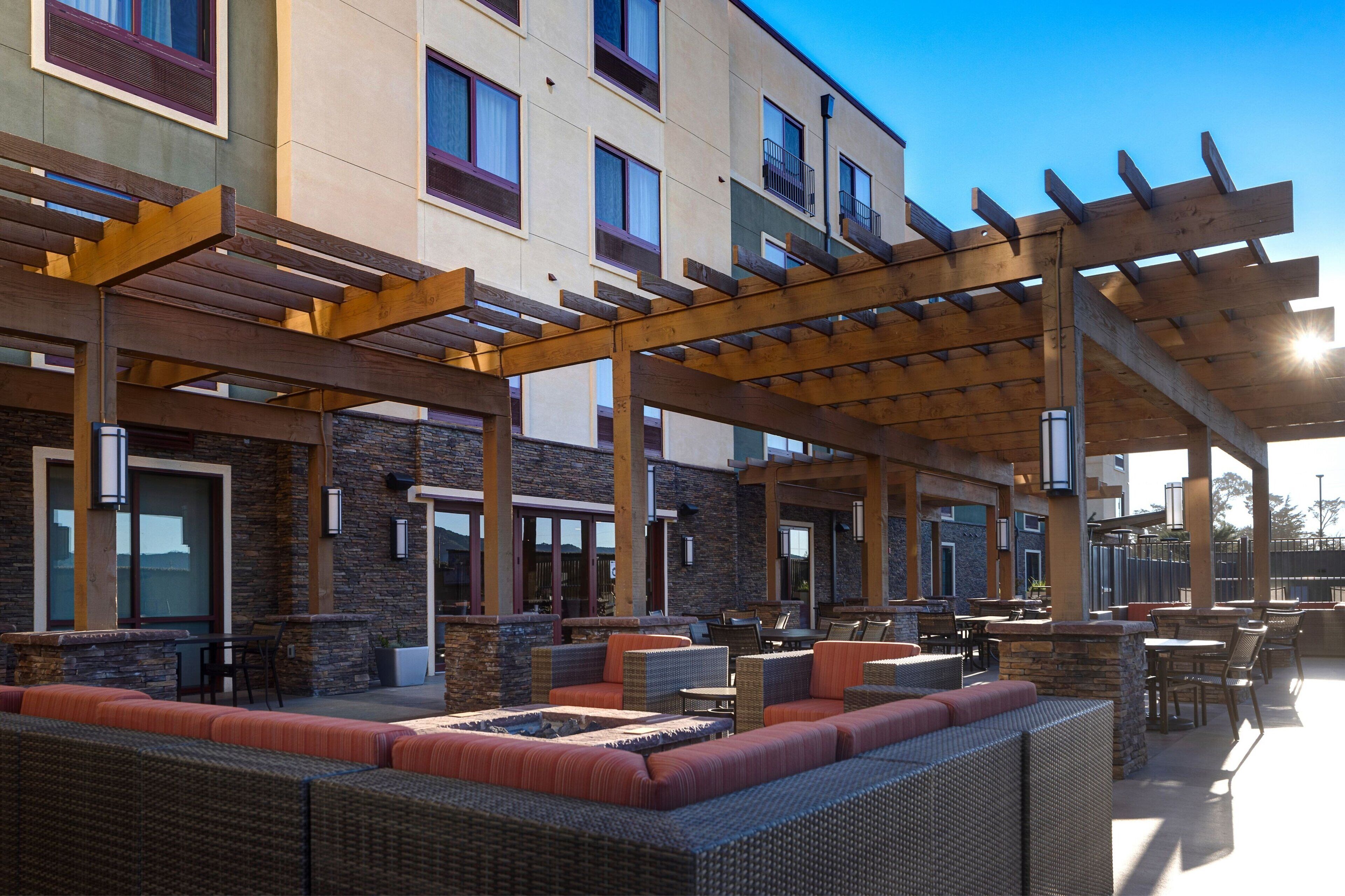 Un espace extérieur aménagé en terrasse, avec des meubles en osier, des éléments décoratifs en pierre et une structure en forme de pergola.