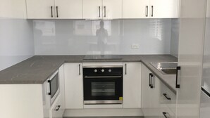 A modern kitchen with white cabinets, a black oven, and a grey countertop.