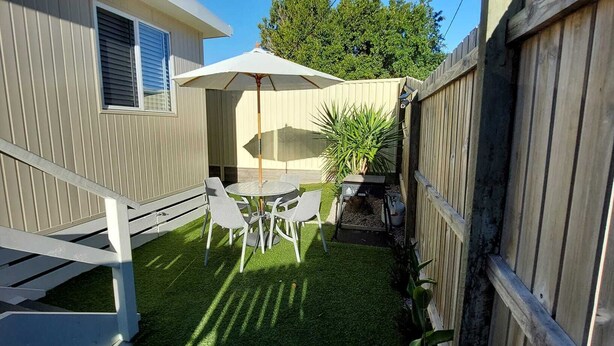 A backyard with a patio table and chairs, a wooden fence, and a white umbrella.