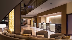 Un vestíbulo de hotel con mostrador de recepción, zona de estar y una escalera.