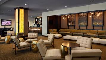 A modern lounge area with sofas, armchairs, and a bar.