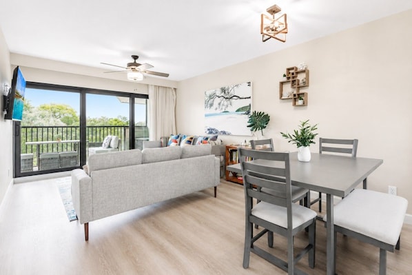 Una sala moderna con sofá, mesa de comedor, sillas y ventilador de techo.