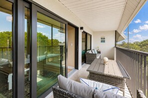 A balcony with a glass door, wicker furniture, and a view of the outdoors.