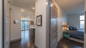 A modern apartment with a spacious living area, a balcony, and a bedroom with a bed and nightstand. - Chic 2BR Condo w/ Open Living Space | Sleeps 4! (Nashville)