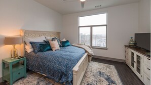 A bedroom with a bed, a nightstand, a TV, a window, and a ceiling fan. - Chic 2BR Condo w/ Open Living Space | Sleeps 4! (Nashville)
