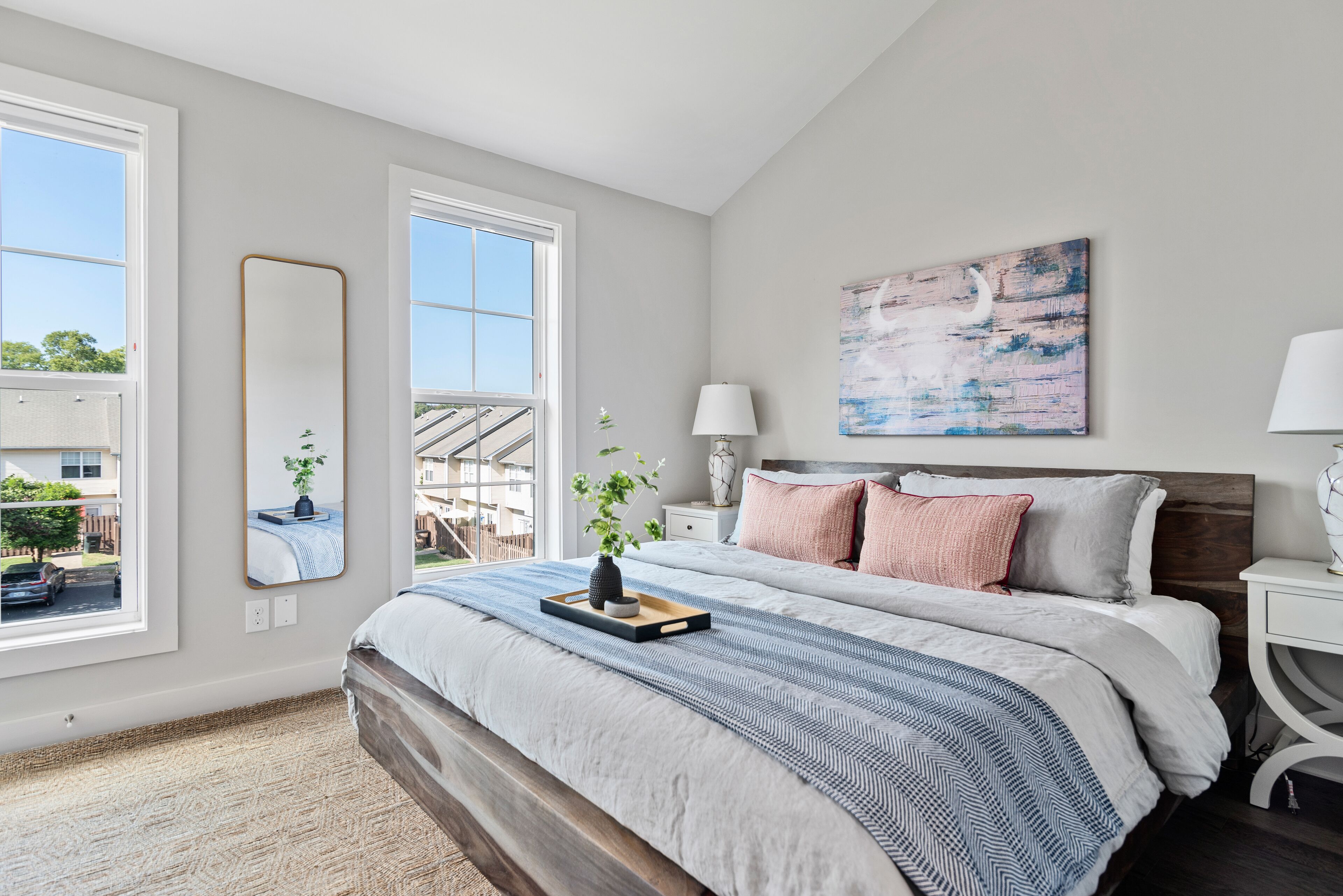 Een slaapkamer met een groot bed, een raam, een schilderij en een nachtkastje.