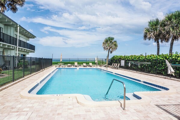 Una piscina rectangular con borde de azulejos, rodeada por un patio de ladrillo.