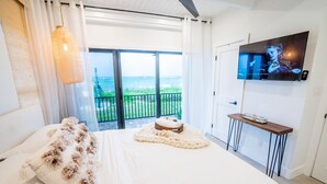 A bedroom with a bed, a television, a view of the sea, and a balcony. - Casa al Mare – Premier "True Beachfront" Living in Vero Beach!  Steps to sand! (Vero Beach)