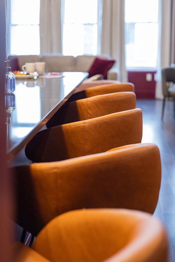 A modern dining area with a long table and several orange chairs.