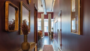 A hallway with a wooden bench, a vase with dried plants, and a rug leading to a dining area with chairs and a table. - Dazzling Downtown Loft in the Heart of Music City (Nashville)