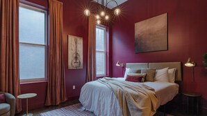 A bedroom with a large bed, a small round table, and a window with curtains. - Dazzling Downtown Loft in the Heart of Music City (Nashville)