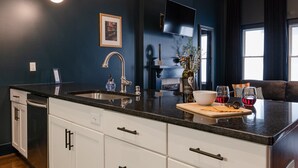 Una cocina moderna con encimera negra, armarios blancos y una isla grande.