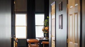 Un pasillo con piso de madera, un comedor con mesa y sillas, y una puerta a la derecha.