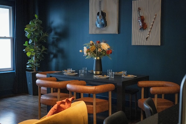 A dining area with a dark blue wall, a violin, and a vase of flowers.