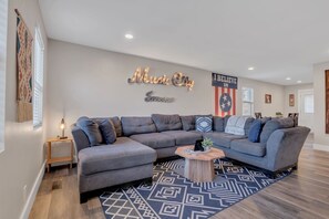 Een moderne woonkamer met een hoekbank, een salontafel en decoratieve muurkunst.