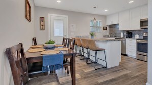 Eine moderne Küche mit weißen Schränken, einem Edelstahlbackofen und einem Essbereich mit Holzkästen und einer blauen Tischdecke.
