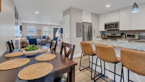A modern kitchen with a marble countertop, stainless steel appliances, and a bar area with stools. - Honky Tonk Hideaway on Music Row (Nashville)