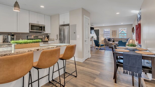 Una cocina moderna con armarios blancos, electrodomésticos de acero inoxidable y una isla central con taburetes de bar.