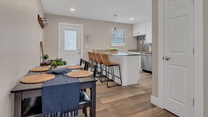 Una cocina moderna con comedor, que incluye una isla central, piso de madera y una puerta blanca.