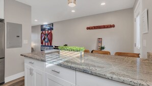 Una cocina moderna con encimera de granito, armarios blancos y una lámpara colgante.
