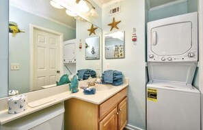 A bathroom with a sink, mirror, and a white washing machine.