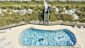 A swimming pool with a wooden deck and a person walking on a boardwalk. - Beachfront Oceanside Condo. Incredible view: Channel Marker  (Surfside Beach)
