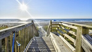A wooden boardwalk leading to a beach with a clear sky and sun shining. - Beachfront Oceanside Condo. Incredible view: Channel Marker  (Surfside Beach)