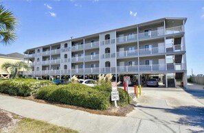 A multi-story hotel with balconies, a parking area, and a sign indicating 'ENTER ONLY'.