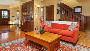 A spacious living room with a wooden coffee table, a red sofa, and a staircase.