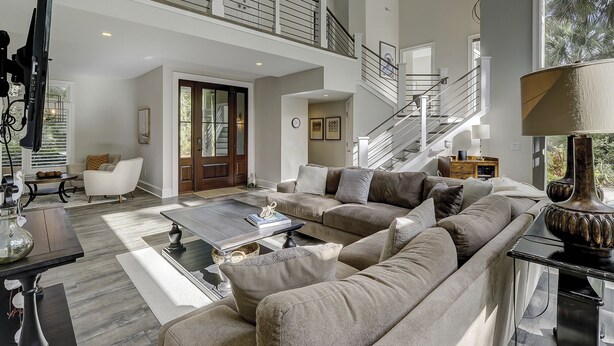 Un salón amplio con un sofá seccional, una mesa de centro y una escalera que conduce a un nivel superior.