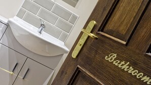 A bathroom with a white sink, a small window, and a door labeled "Bathroom". - Hanbury Turn (Bromsgrove)