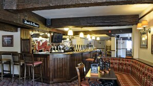 A bar area with wooden furniture, a dragon decoration, and a variety of bottles. - Hanbury Turn (Bromsgrove)