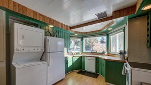 Eine Küche mit grünen Schränken, einem weißen Kühlschrank und Holzboden.