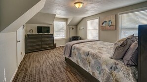 Ein Schlafzimmer mit Bett, Kommode und Fernseher auf einem Tisch.