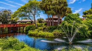 Ein friedlicher Garten mit Teich, einer Holzbrücke und einem Pavillon.