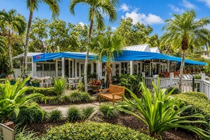 Restaurante con terraza al aire libre, rodeado de palmeras y plantas tropicales.