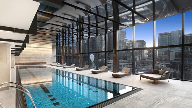 Ein moderner, überdachter Pool mit Glaswänden, Liegestühlen und Blick auf die Stadt.