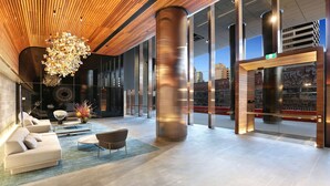 Eine moderne Lobby mit Holzboden, großen Glasüren und einer zentralen Säule.