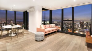 Ein modernes Wohnzimmer mit Stadtblick, einem runden Esstisch, einer Couch und einem kleinen Hocker.