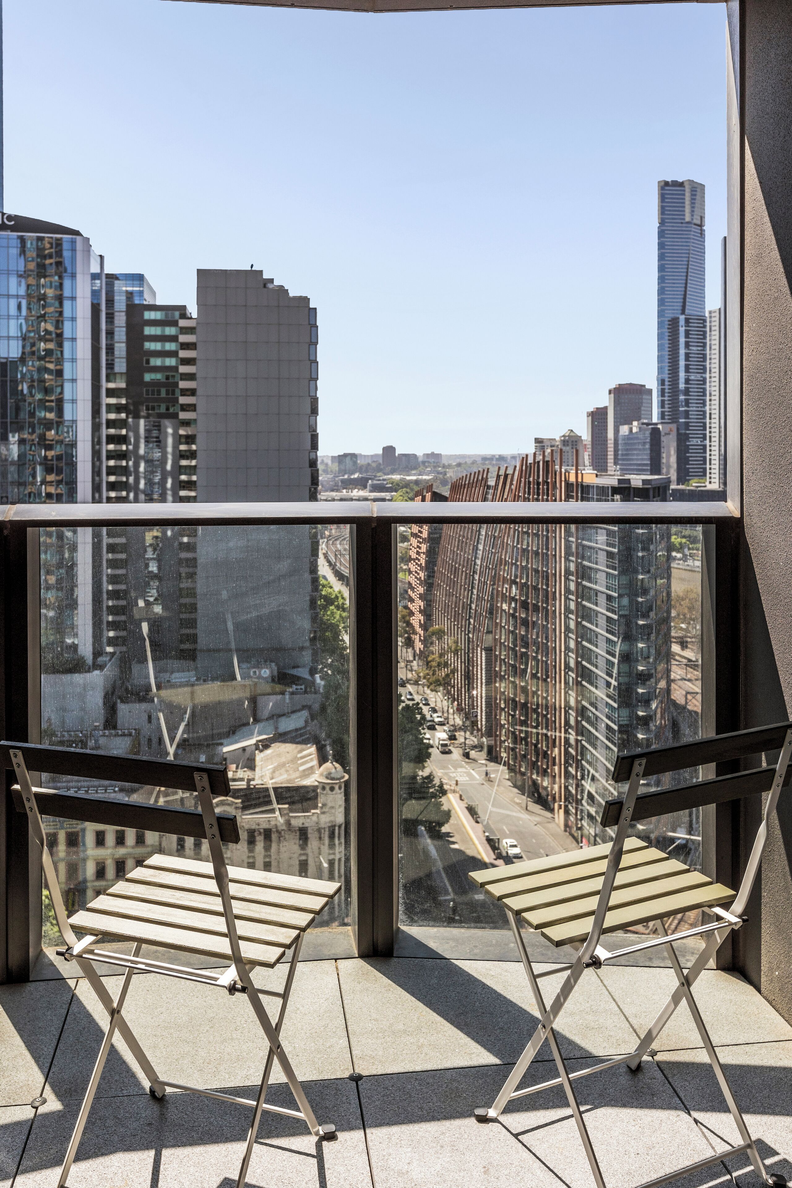 A balcony with two folding chairs and a view of a cityscape with tall buildings.