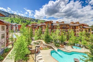 A resort with a swimming pool, a water slide, and a mountainous backdrop. - Newly updated Solitude Resort Village Ski in and Ski out Condo!! (Salt Lake City)