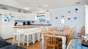 Une cuisine moderne avec des meubles blancs, une table à manger en bois et un îlot central intégré.
