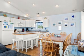 A modern kitchen with white cabinets, a wooden dining table, and a built-in island.