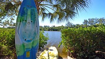 Un kayak sur lequel est écrit le mot « Beat », un kayak jaune, et une étendue d’eau avec des arbres en arrière-plan.