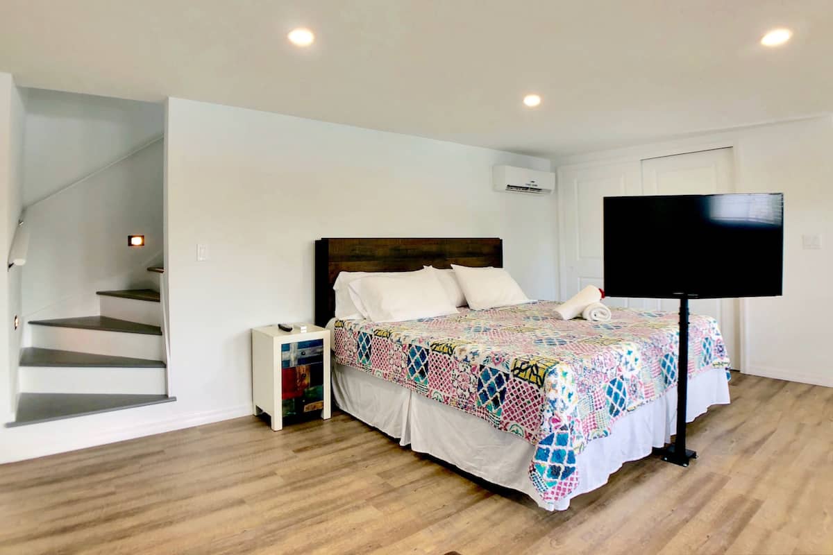 Une chambre à coucher avec un lit, une télévision, une table de chevet et un escalier.